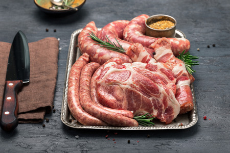 Set of different meat products on an iron tray on a dark surface close upの写真素材