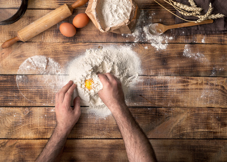 Man cooking dough on wooden table in bakery, top viewの写真素材
