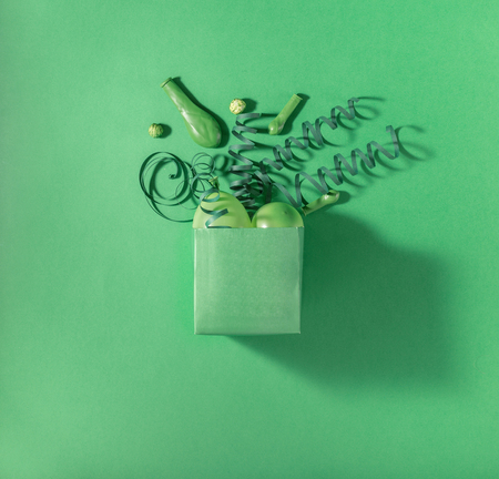 Green gift box with green balloons and green streamers on a green background. Flat layの写真素材