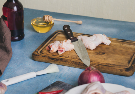 Chicken wings on a wooden board on the kitchen table with ingredients for cooking a healthy dishの写真素材