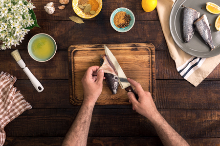 Man cooking fish on a rustic wooden table. Healthy food and diet concept, top viewの写真素材