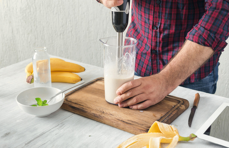 Man cooking a delicious milkshake with a banana in a home kitchenの写真素材