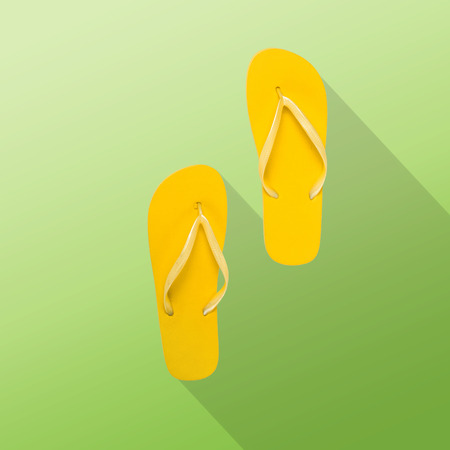Flat lay summer background. Yellow flip-flops on green backgroundの写真素材