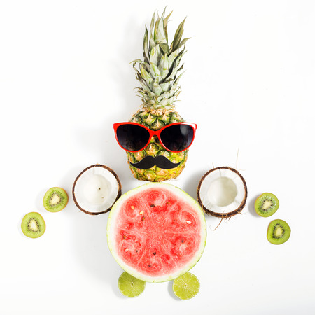 Creative layout made of funny pineapple with sunglasses and different fruits on a white background. Flat lay. Tropical summer vacation conceptの写真素材