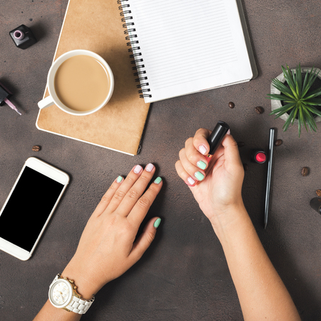 Flat lay hands of women with colorful summer manicure on dark stone surface, top viewの写真素材