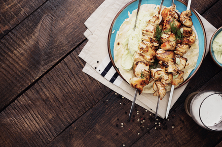 Barbecued chicken breast skewers with avocado sauce on dark wooden table with copy space, top viewの写真素材