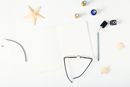 Open notebook on white background with starfish, shells, glasses, pencil and nail polish. Flat lay, top view feminine summer backgroundの写真素材