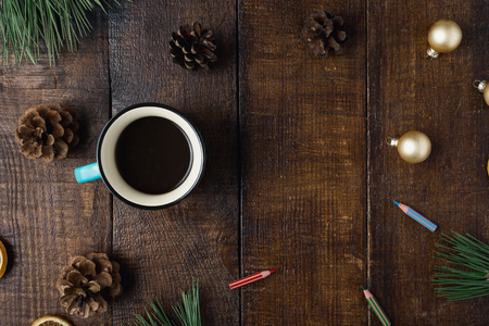 Christmas holidays composition on brown wooden background with cup of coffee, pine cones, Christmas balls,  colored pencils and Christmas tree branches, top viewの写真素材