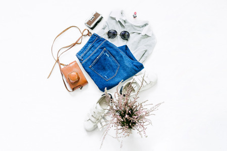 Look female clothes on a white background. Female polo with jeans, lipstick, sunglasses and white sneakers on white background. Beauty blog concept. Flat lay. Top viewの写真素材