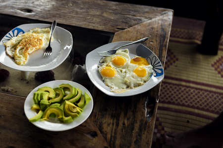 Fried eggs breakfast with avocado on wooden table.の写真素材