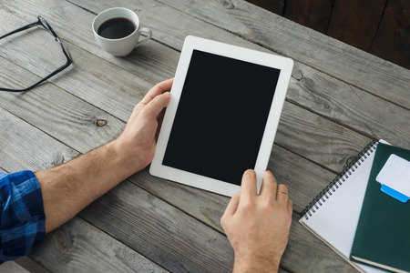 Home workplace, top view. Digital tablet in man hand close up