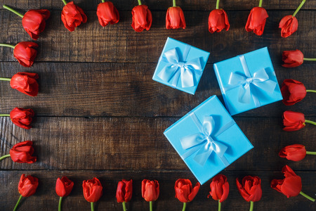Set blue gift box with red tulips on dark wooden background with copy space, top viewの写真素材