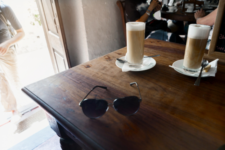 Two glasses of latte on a wooden table in a cafeの写真素材