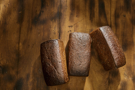 Three loaf of rye bread on dark wooden table with copy space, top viewの写真素材