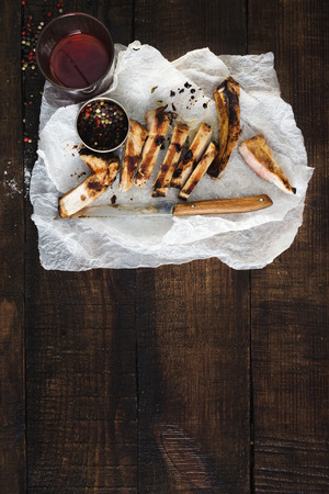 Sliced steak with glass of red wine on dark wooden background with copy space, top viewの写真素材