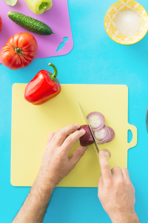 Man cooking summer vegetarian salad on blue background. Healthy food concept. Diet foodの写真素材