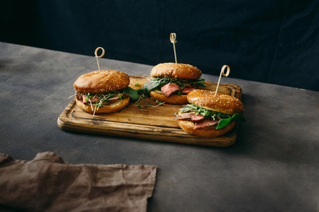 Set burger with beef medium rare, spinach, green sauce and micro greens on wooden cutting boardの写真素材