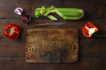Old wooden cutting board with fresh vegetables on dark wooden table, top viewの写真素材