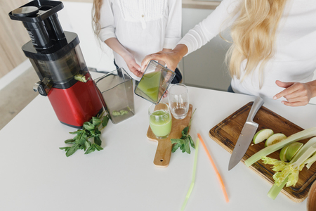 Mom and daughter preparation detox cocktail from celery, apple and mint in the home kitchen, top view. Healthy lifestyle conceptの写真素材