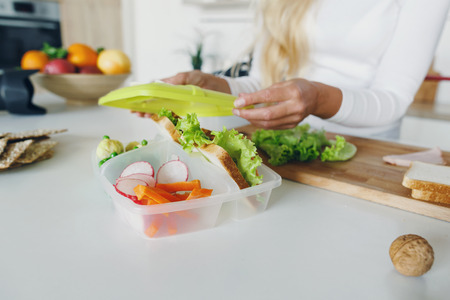 Mother preparing school lunch for childrens in home kitchen