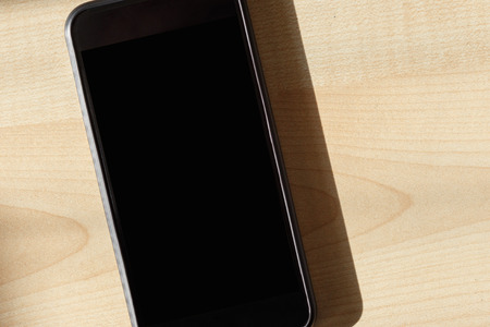Flat lay black smartphone close up on wooden table, top viewの写真素材