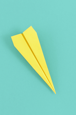 Flat lay yellow paper plane on pastel blue background. Top view creative travel background conceptの写真素材