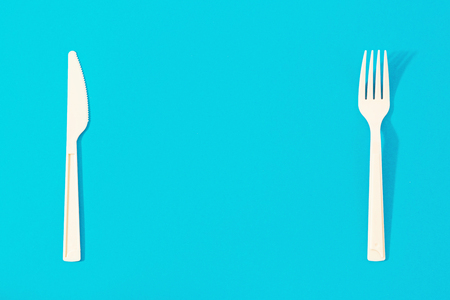 Flat lay knife and fork on blue background. Top view minimalist food backgroundの写真素材