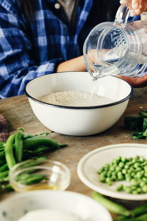 Healthy food concept. Raw ingredients for cooking risotto on wooden table. Woman cooking vegetarian risotto with green peas, mint and goat cheeseの写真素材