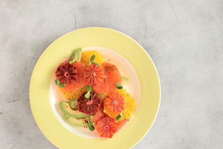 Healthy and dietary food concept. Plate of healthy summer fruit salad made of oranges, grapefruit and avocado on white concrete background. Top view, flat layの写真素材