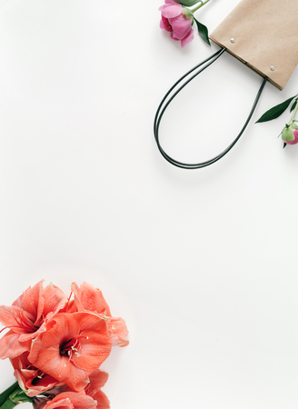 Frame of paper hand bag with flowers amaryllis and peonies on white background. Flat lay, top view. Congratulations backgroundの写真素材