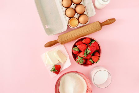 Raw ingredients for cooking strawberry pie on pink background  (eggs, flour, milk, sugar, strawberry), top view, flat lay. Bakery background. Recipe for strawberry pieの写真素材