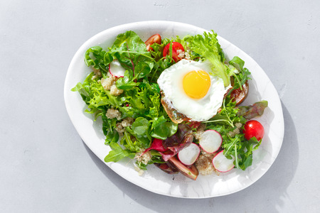 Plate fresh salad with quinoa and fried egg on gray concrete background. Healthy food clean eatingの写真素材