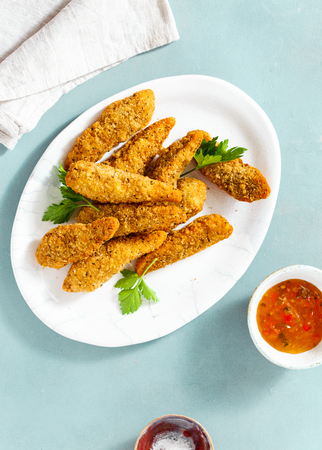 Chicken breast nuggets with sour-sweet sauce on blue background top viewの写真素材