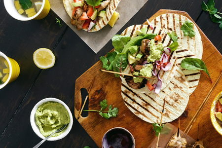 Tacos grill with vegetable salsa, guacamole sauce and chicken on dark wooden background with lemonade top viewの写真素材