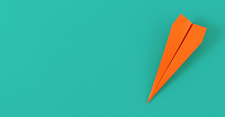 Flat lay colorful paper plane on pastel turquoise background with copy space. Top view creative travel background conceptの写真素材