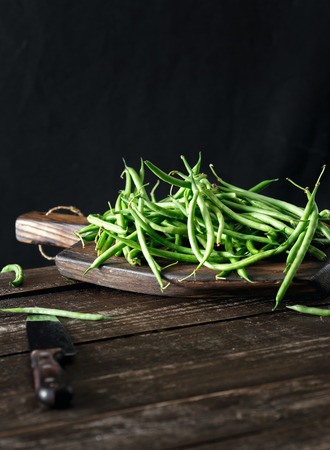 Raw green bean on wooden cutting board on dark background. Healthy, vegetarian food conceptの写真素材