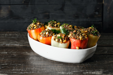 Healthy, vegetarian food concept. Raw green lentils, corn and salsa stuffed peppers in baking dish on wooden table copy spaceの写真素材
