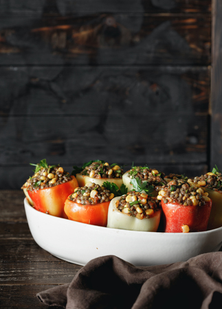 Raw stuffed peppers with green lentils, corn and salsa in baking dish on wooden table copy space. Healthy, vegetarian food conceptの写真素材