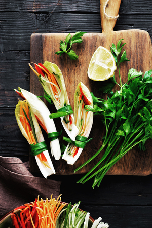 Vegetable roll with chicory leaves, pepper, carrot and cucumber on dark wooden background. Vegetable snacks. cooking raw food conceptの写真素材