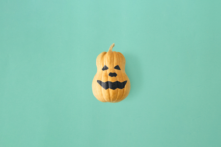 Flat lay funny scary face Halloween pumpkins on turquoise background. Fall autumn halloween minimal concept top viewの写真素材