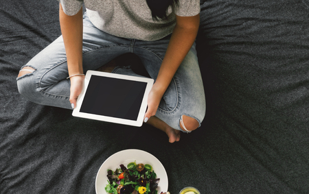 Woman hands holding digital tablet with empty blank screen sitting on bed, top viewの写真素材