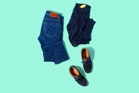 Flat lay set autumn male clothes jeans, pullover and shoes on turquoise background top viewの写真素材