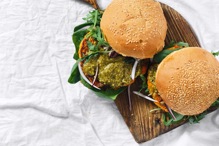 Healthy vegetarian food concept. Vegetarian burger made of pumpkin cutlet, spinach, arugula and pesto sauce served on a wooden board top view copy spaceの写真素材
