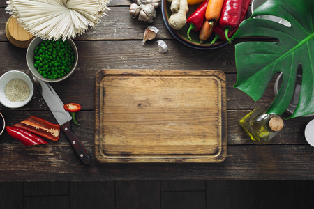 Around empty cutting board raw ingredients for cooking vegetarian thai noodles on dark wooden table in home kitchen top viewの写真素材