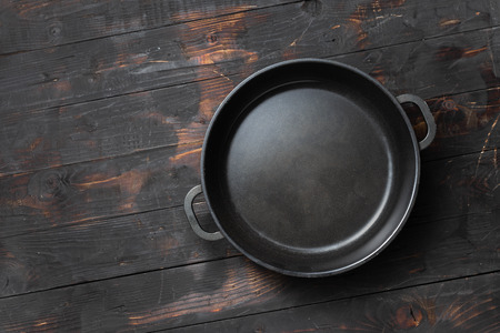 Empty pan on dark wooden kitchen table top viewの写真素材