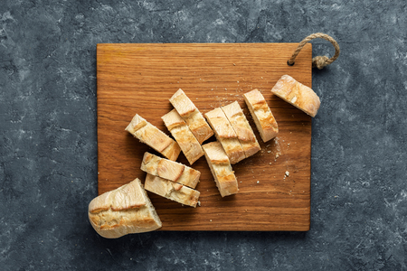 Fresh baguette slices on wooden border on dark stone background top viewの写真素材