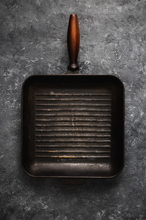 Empty old grill pan on dark stone background top viewの写真素材