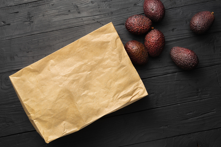 Paper bag with fresh avocado hass in the box on wooden dark background top viewの写真素材