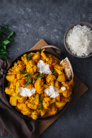 Vegetarian indian food. Cauliflower curry with basmati rice and naan bread on dark stone background top view. Healthy and tasty food conceptの写真素材