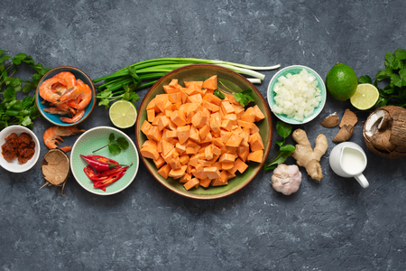 Raw ingredients for cooking sweet potato soup with shrimps on dark  top viewの写真素材